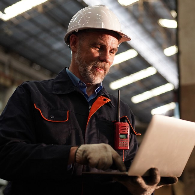A construction worker smiles and works on a computer